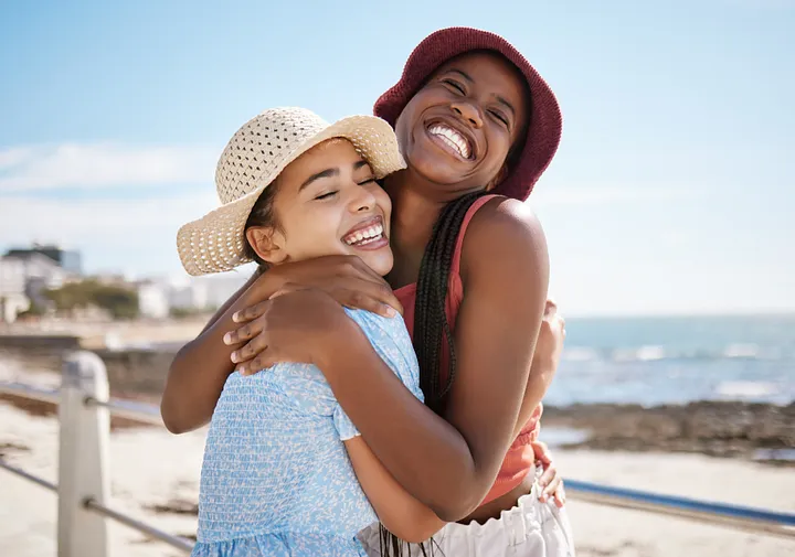 two people smiling and hugging on a beach