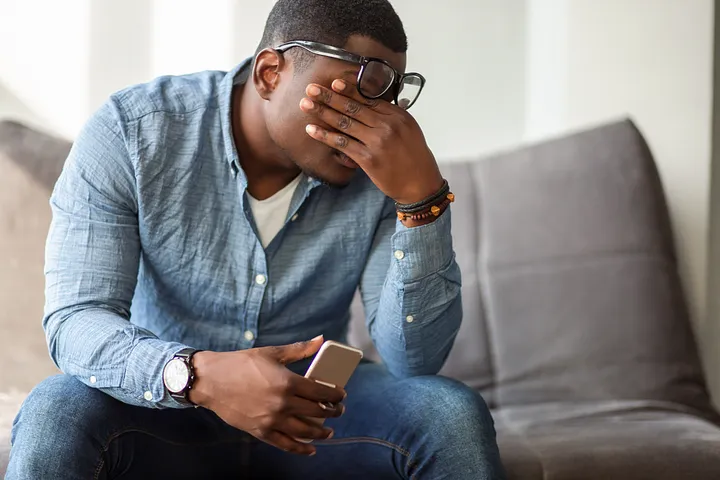 man with glasses holding his head