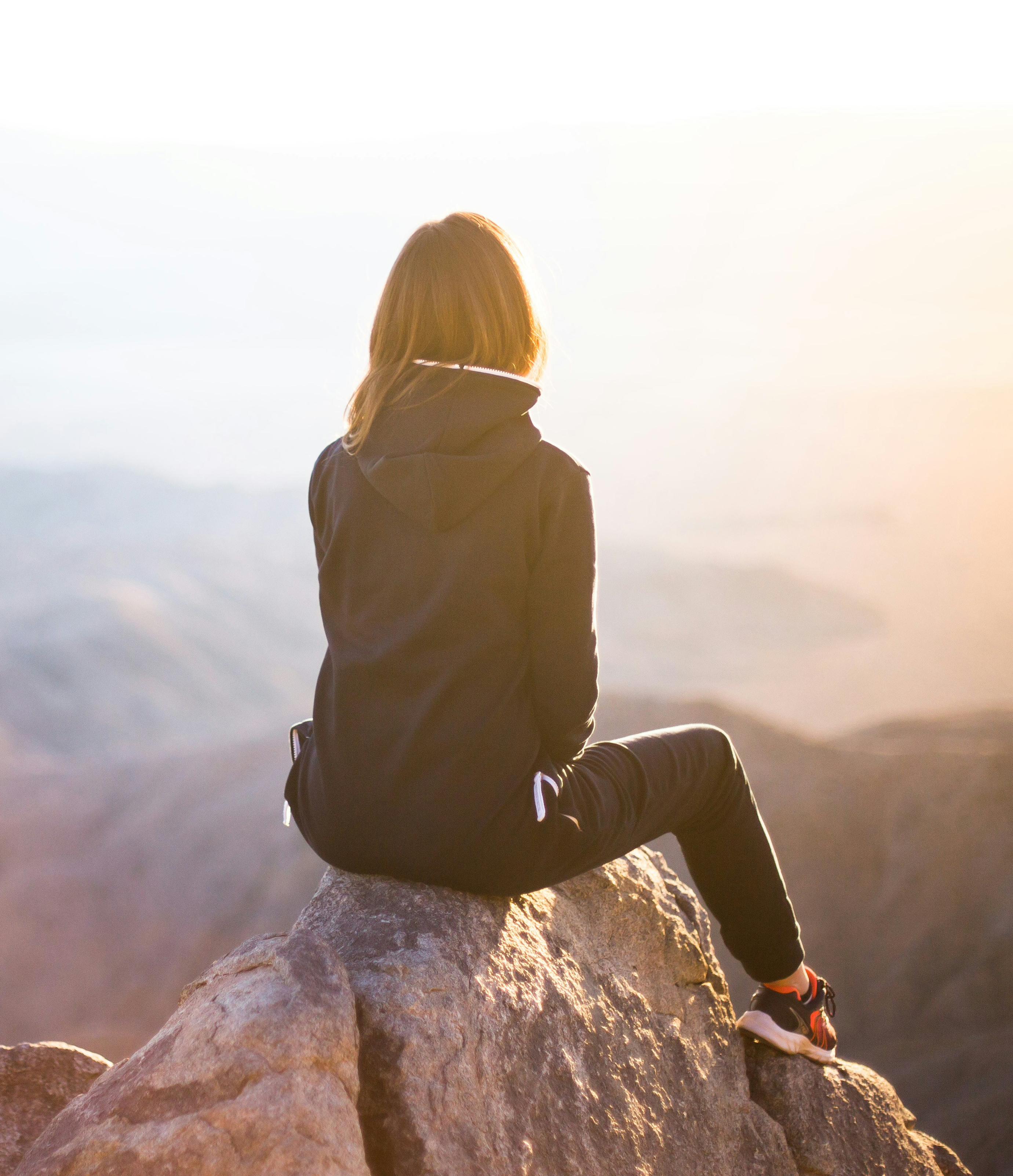 woman sitting on a mountainside looking into the distance